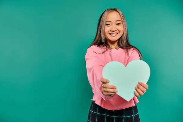 stock image 14 february concept, cheerful asian woman holding heart shaped carton on turquoise background