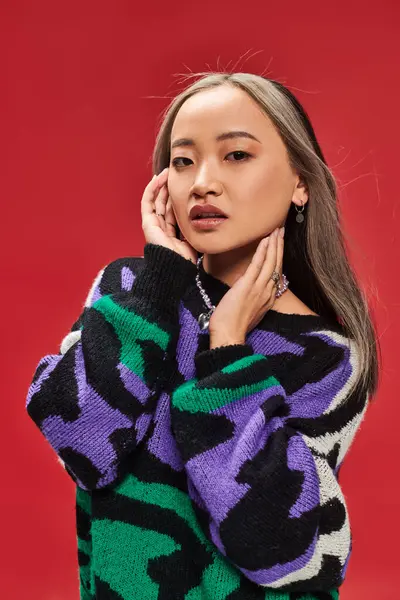 stock image beautiful young asian woman with dyed hair in sweater with animal print posing with hands near face