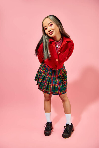 стильная азиатская молодая женщина с валентинками день макияж глаз позируя на розовом фоне, форма сердца