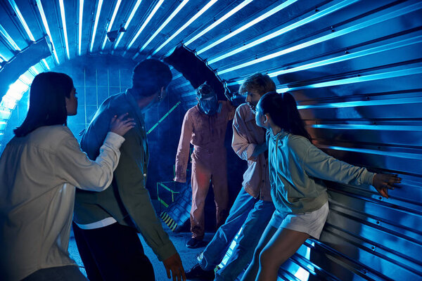 испуганные разнообразные друзья, стоящие в туннеле рядом с чудаковатым человеком в противогазе, участие в квесте