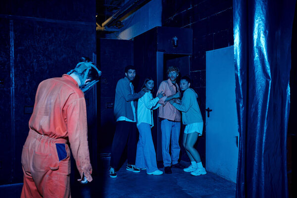 человек в газовой мачте, стоящий рядом с испуганными мультикультурными друзьями в комнате побега, приключения