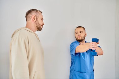 Genç ve yetenekli bir doktor, Klişe Merkezi 'nde dambılla nasıl antrenman yapılacağını gösteriyor.