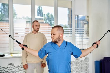 Mavi üniformalı yetenekli bir doktor Kinesio Merkezi 'nde egzersiz makinesi eğitmeni.