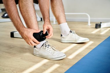Modern Kinesio Merkezi 'nde iyileşme eğitiminden önce spor kemeri takan bir adam.