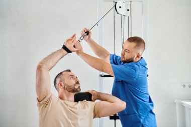 Kinesio Merkezi 'ndeki egzersiz makinesinde iyileşme eğitimine yardım eden yetenekli bir hekim.