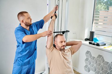 Kinesio Center 'da egzersiz makinesinde insan eğitimini destekleyen yetenekli bir rehabilitasyon uzmanı.