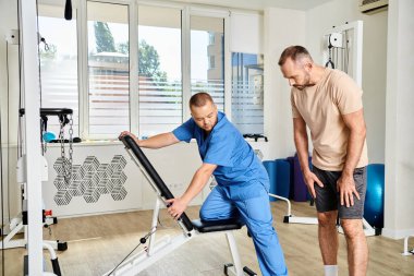 Kineziyoloji merkezinde iyileşme eğitiminden önce mavi üniformalı genç bir doktora danışmanlık yapıyorum.