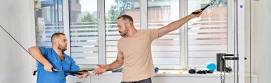 Genç rehabilitolog adamı Kinesio Center 'da egzersiz makinası eğitimi için hazırlıyor.