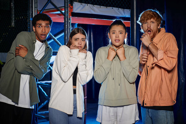 group of diverse and astonished young people looking at camera and discovering a clue in escape room