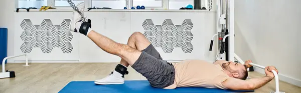 stock image side view of man lying down on fitness mat during recovery training in kinesio center, banner