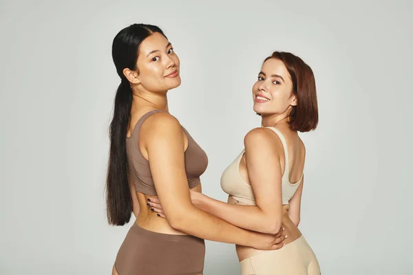 Radostná Asijská Žena Objímající Svou Přítelkyní Spodním Prádle Při Pózování — Stock fotografie
