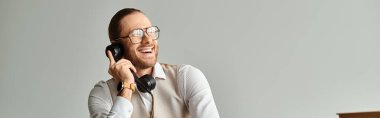 joyous handsome man with beard and glasses talking by retro phone and looking away, banner clipart
