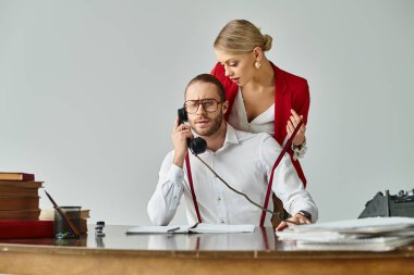 focused handsome bearded man talking by retro phone while his girlfriend hugging him, work affair clipart