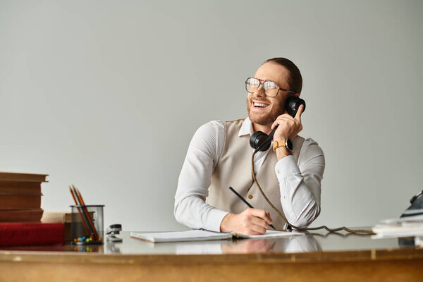cheerful young man with beard and glasses talking by retro phone and taking notes, smiling happily