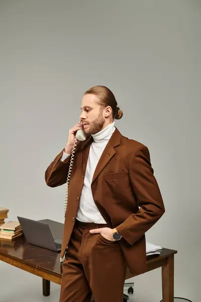 stock image handsome young male model in brown stylish jacket talking by vintage phone with hand in pocket