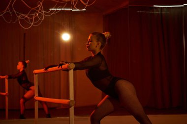 Tayt ve tayt giymiş zarif bir dansçı koreografisini barda, dans hareketlerinde mükemmelleştirir.