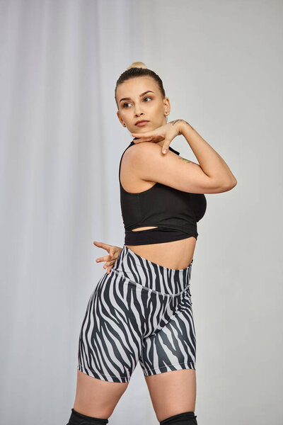 изящная женщина элегантно позирует и демонстрирует свои определенные плечи во время танцев в студии