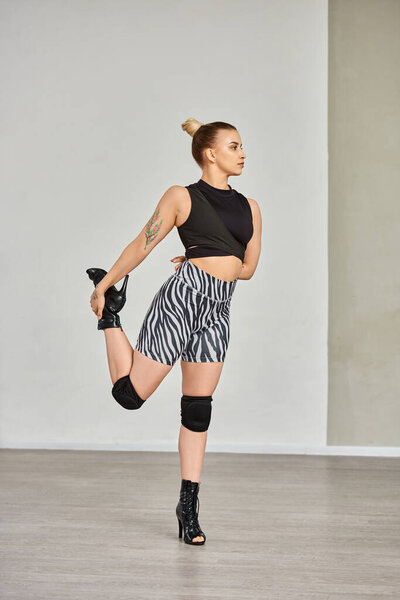 woman gracefully stretches leg in zebra shorts and high heels, displaying balance and flexibility
