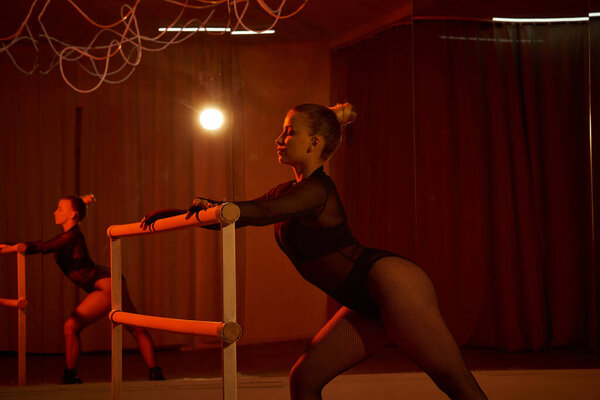 Изящная танцовщица в трико и трико совершенствует свою хореографию в баре, танцевальные движения