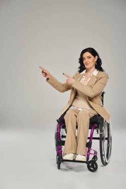good looking woman with ability disability sitting in wheelchair and gesturing, looking at camera clipart