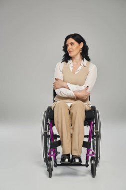 Çekici esmer, engelli, şık giyimli, tekerlekli sandalyesinde oturan ve başka tarafa bakan bir kadın.