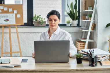 Tekerlekli sandalyedeki şık giyimli kendini işine adamış güzel bir iş kadını laptopuyla çalışıyor.