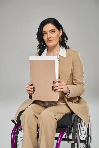 привлекательная уверенная в себе женщина с ограниченными возможностями держит свои документы и смотрит в камеру