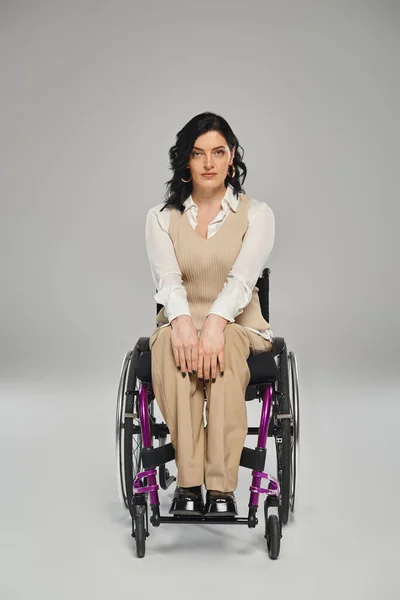 Stock image beautiful disabled woman in pastel elegant attire sitting in wheelchair and looking at camera