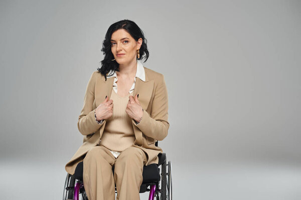 уверенная в себе женщина с ограниченными возможностями в элегантном костюме пастели сидит в инвалидном кресле и смотрит в камеру
