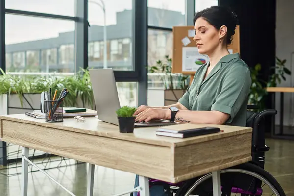 stock image good looking confident woman with disability in wheelchair working hard at her laptop in office