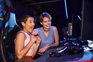 Heyecanlı ve dövmeli kadınlar bilgisayar kulübündeki bir siber spor oyununa konsantre oluyorlar, kadın oyuncular.