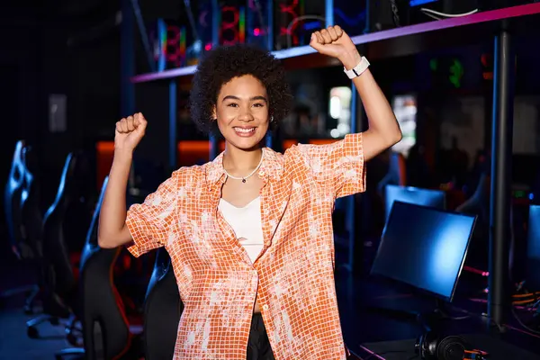stock image african american woman in vibrant clothing, her face radiating with joy and standing with arms up