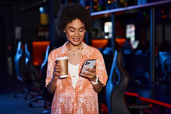 Tarz Sahibi Afro Amerikan Kadın Elinde Kahve Telefonu Ortamında Gülümsüyor — Stok fotoğraf