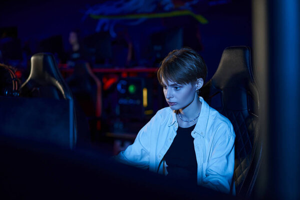 сфокусированная женщина смотрит на монитор во время игры в многопользовательскую компьютерную игру, женщина-геймер рядом с ПК