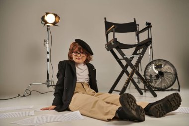 boy in glasses and beret sitting on floor surrounded by screenplay, boy as director of filmmaker clipart