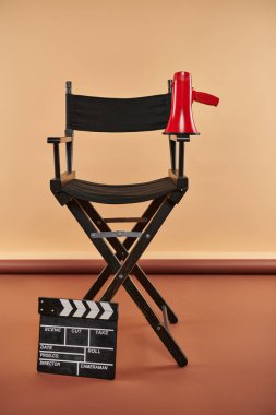 Yönetmen koltuğu dik duruyor, megafon ve alkış tahtası ile süslenmiş, sinematografi konsepti