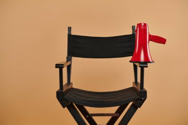 a director chair with a red megaphone on beige background, cinematography and production concept clipart