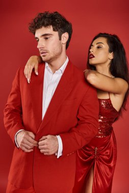 Çekici, kırmızı dudaklı genç bir kadın Sevgililer Günü 'nde takım elbiseli yakışıklı bir adamın omzuna yaslanıyor.