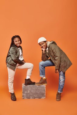 joyful preadolescent african american boy and girl posing together and smiling happily at camera clipart