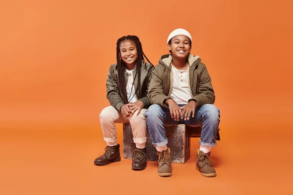 Stock image cheerful preadolescent african american boy and girl sitting and smiling happily at camera