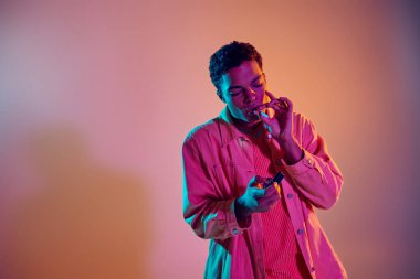 Havalı Afro-Amerikan bir adam sigarasını yakarken mavi neon ışıkların altında pembe