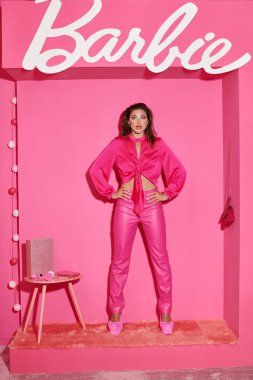 KYIV, UKRAINE - 14 Temmuz 2023: Kırpılmış bluzlu kadın ve pembe pantolonlu kadın gibi pembe odada elleri kalçalarında duran Barbie,