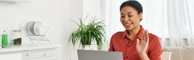 Mutlu Afro-Amerikan beslenme uzmanı mutfaktaki bilgisayarından online danışmanlık sağlıyor.