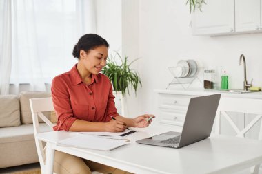 Mutfaktaki dizüstü bilgisayarda yapılan bir danışma sırasında elinde ilaç tutan mutlu bir kadın dietisyen.