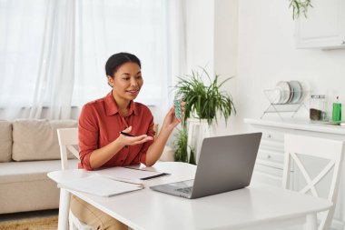 Mutfaktaki dizüstü bilgisayarında ilaç tedavisi gören gülümseyen bir kadın beslenme uzmanı.