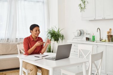 Neşeli beslenme uzmanı mutfaktaki dizüstü bilgisayarda yaptığı bir muayenede ilaç gösteriyor.