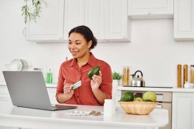 Afrikalı Amerikalı beslenme uzmanı avokado ve takviye maddeleri tutarken internette diyet tavsiyesi veriyor.
