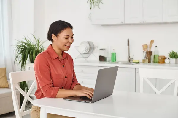 stock image happy african american nutritionist using laptop while working remotely from her kitchen