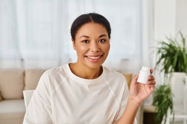 Afro-Amerikan beslenme uzmanlarının portresi sağlıklı beslenmek için bir şişede takviyeler tutuyor.