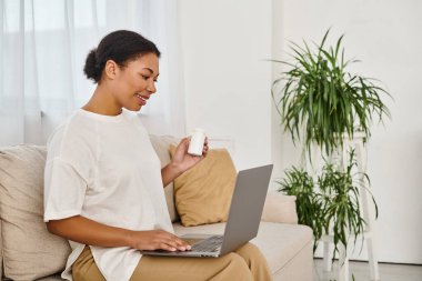african american nutritionist with supplements giving dietary advice via laptop in living room clipart